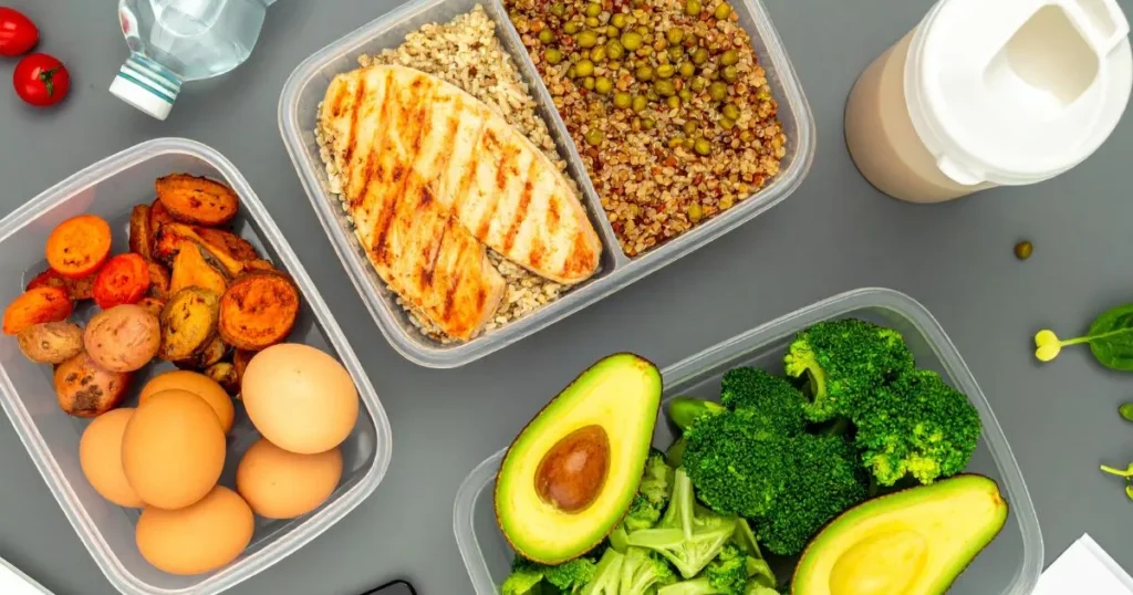 Clean and organized bulking meal prep layout with high-protein foods like chicken, rice, sweet potatoes, and vegetables in glass containers on a kitchen counter.