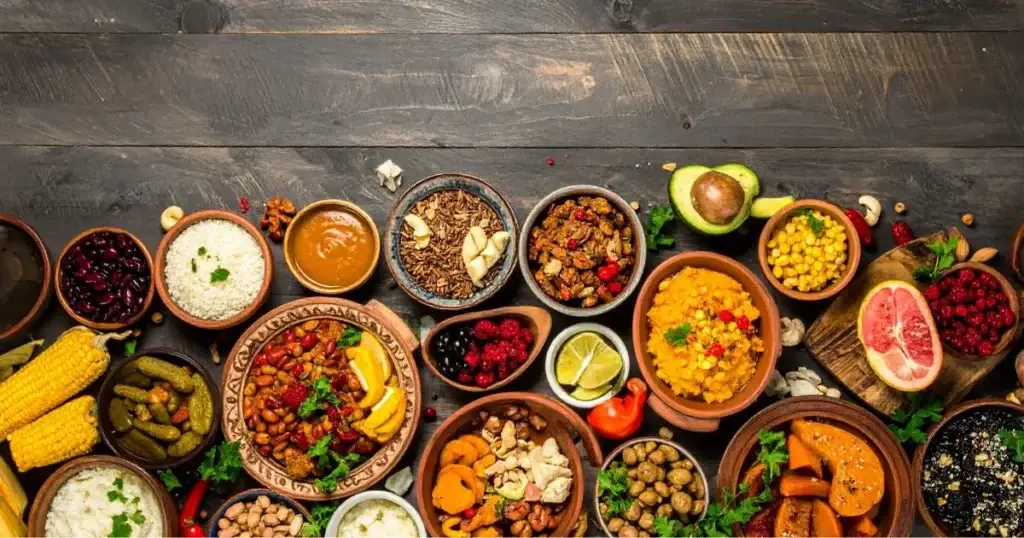 A colorful assortment of traditional Native American foods, including corn, beans, squash, wild rice, berries, and nuts, beautifully arranged on rustic wooden platters and clay bowls, highlighting the diversity and heritage of Indigenous cuisine.