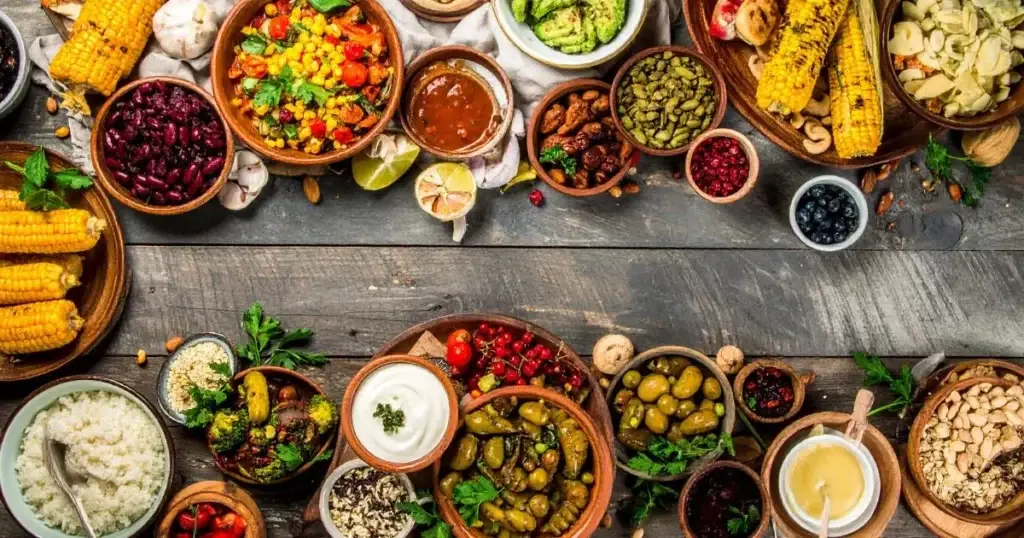 A colorful assortment of traditional Native American foods, including corn, beans, squash, wild rice, berries, and nuts, beautifully arranged on rustic wooden platters and clay bowls, highlighting the diversity and heritage of Indigenous cuisine.