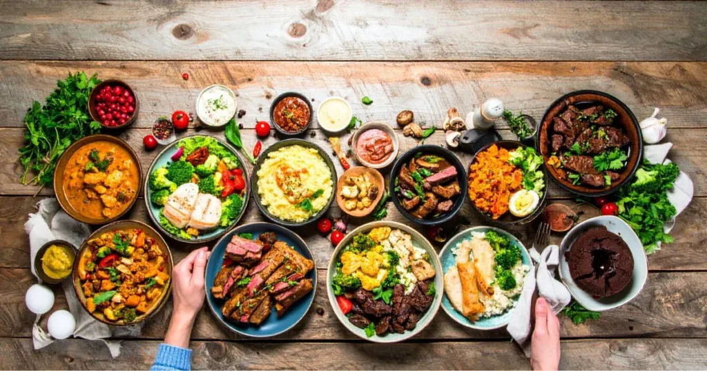 Assorted keto Instant Pot recipes including low-carb chicken, beef, vegetables, and dessert dishes, served in bowls on a rustic kitchen table